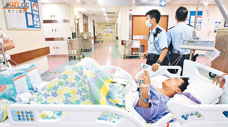 其中一名疑犯在屯門醫院留醫，由兩名警員看守。（譚佩蓮攝）