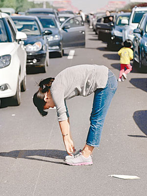 一名女子在京滬高速天津段公路上做體操，舒展筋骨。（中新社圖片）
