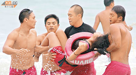 一名遇溺的女泳客由救生員合力救上岸。