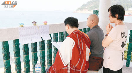 三名藏傳佛教信眾對着海面為死難者誠心誦經。（陳桂建攝）