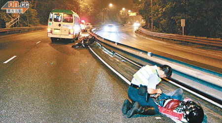 鐵騎士倒臥路旁，警員為他檢查傷勢。（沈厚錚攝）