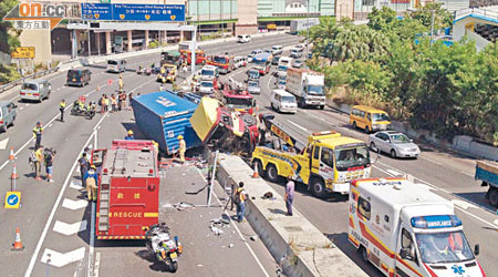 貨櫃車擦壆撞燈柱後，車頭擱於壆上，貨櫃壓落對面行車線。（吳欽旺攝）