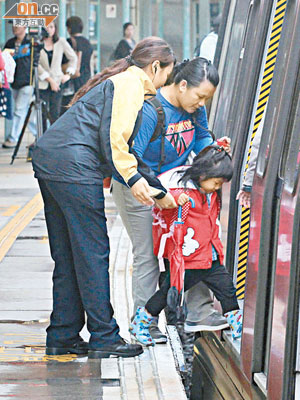 東鐵線大學站月台與車廂間空隙寬闊，小朋友需在港鐵職員及家長扶助下小心登上列車。（袁志豪攝）