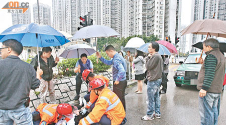 男生被的士撞倒重傷，學校老師及途人為傷者舉傘擋雨。（林明強攝）