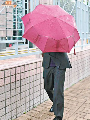 被告黃栢年昨離庭時用傘遮掩外貌。