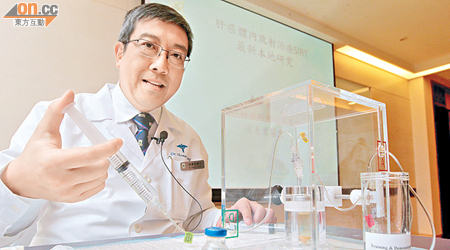 梁惠棠示範體內放射治療，用注水的針筒將膠盒中放射物送到前方的膠樽，模擬放射物注入病人體內。