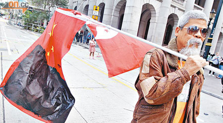 古思堯在元旦倒梁遊行當日手持塗黑了的中國國旗及香港區旗，被控侮辱國旗及區旗罪。（資料圖片）