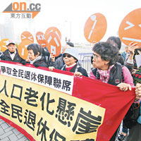 有示威者「惡搞」施政報告宣傳片內的橙色圓形面具，要求政府落實全民退休保障。（蕭毅攝）