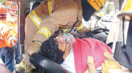 南亞裔司機被夾於客貨車上，正由消防員拯救。（林明強攝）