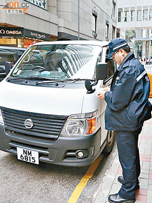 廉署人員與劉夢熊在中環公司時，廉署專車疑違泊在禁區被警員「抄牌」。（鍾健國攝）