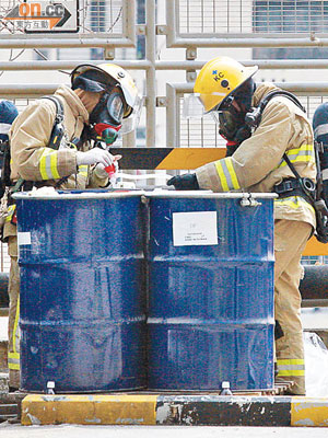 消防員穿上保護裝備，檢查疑盛載天拿水的鐵桶。 （何仲軒攝）
