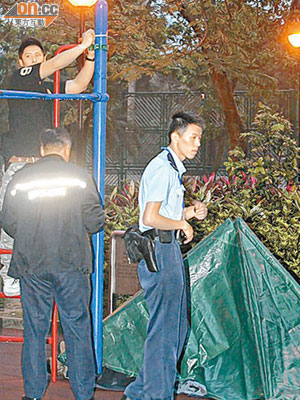 警員用帳篷蓋着吊頸男子的屍體，並量度他在攀爬架上吊的高度。（楊日權攝）