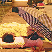 有學生在雅安市內的四川農業大學教學樓前路邊撐起雨傘過夜。（中新社圖片）