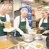 炒好麵條後，陳光明（左）將麵分入飯盒中，一千個午餐飯盒就大功告成。
