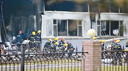 消防員陸續在火場抬出遇難者遺體。（中新社圖片）