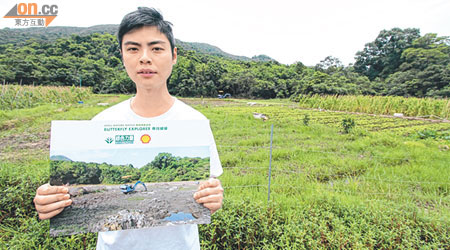 單家驊展示身後大片淡水濕地去年遭破壞的相片，該處現暫已復耕。（梁鵬威攝）