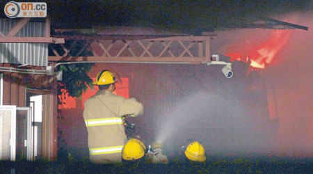 消防員向起火傢俬貨倉射水灌救。（文健雄攝）