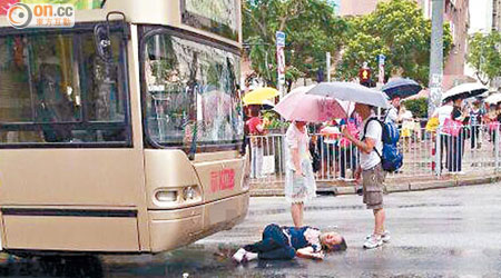 老婦被巴士撞傷倒地，街坊為她打傘擋雨。（網民Ken Lau提供）