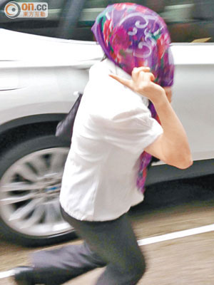 被告譚彩鳳為逃避記者鏡頭，以絲巾掩臉離去。