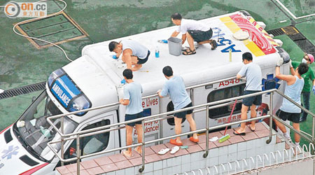 上周五高掛三號風球，大埔救護站各人仍冒着風雨清潔救護車。（梁耀榮攝）