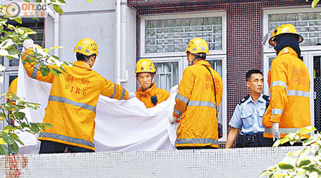 消防將平台上的半截屍體移到地面。外牆沾有死者血漬。（馬竟峯攝）