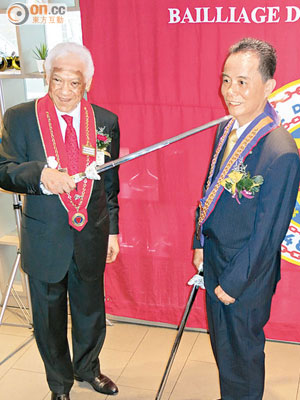 古載禮（左）用劍放在劉榮坡（右）肩膊上，以示對頒授勳帶係神聖同莊嚴。（潘翠華攝）