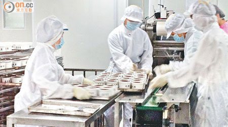 廠房內的瓦裝龜苓膏生產線，多名穿着保護衣的職工在包裝。（張琦攝）