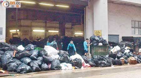 上海街臨時垃圾收集站清潔工開工未幾，即要清理門外堆積逾百袋垃圾。（讀者提供）