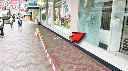 銀行櫥窗被毀（箭嘴示），瓷磚粉碎散落地，警方封路調查。
