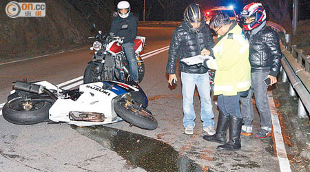 電單車撞防撞欄後橫亘路中，並漏出燃油。（梁國雄攝）