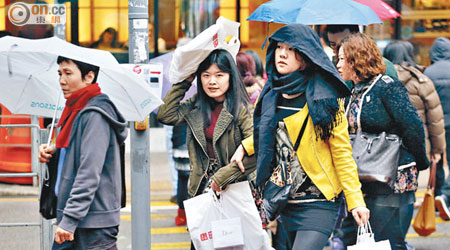 又凍又有雨，既要打傘擋雨，也要圍頸巾保暖。（盧志燊攝）