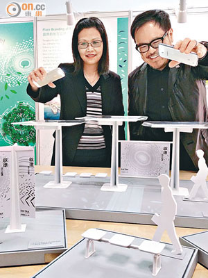 啟德辦專員李關小娟（左）與設計顧問劉小康利用手提電話的燈光，照射涼亭模型，營造樹影氣氛。