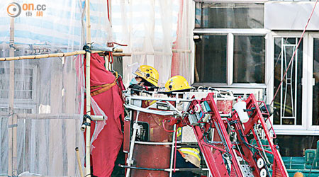 消防員乘升降台到七樓將遺體移下。（莊杰成攝）