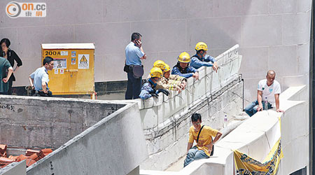 兩名工人危坐在大廈三樓平台石壆。（陳展鴻攝）