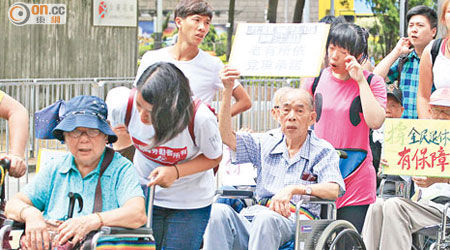 天氣驟雨驟晴，坐輪椅長者一樣帶頭遊行爭全民退保。（高嘉業攝）