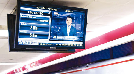 北京西單地鐵站內播放《新聞聯播》有關周永康受查的報道。（中新社圖片）
