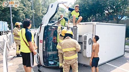 貨車失事翻側，消防員協助被困司機及跟車爬出車外。（林健森攝）