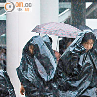 市民用大膠袋充當雨衣，逆風急走。（蕭毅攝）