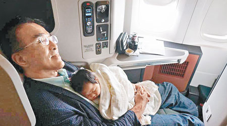 田北辰飛往加國途中，在飛機上攬住孫女瞓足全程。（互聯網圖片）