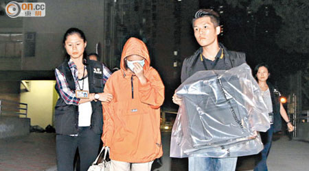 涉案女文員手挽名牌手袋被帶署，探員從其住所檢走電腦。 （王譯揚攝）