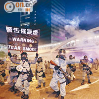 金鐘<br>手持長槍和防毒面罩的防暴警察，在一片催淚彈下逐步向示威者推進。（梁鵬威攝）