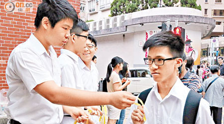 一間中學校門外，有學生向同學派發黃絲帶。