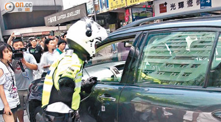 交通警員調查企圖拆路障的私家車司機。