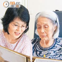 馮淑敏（圖左）與母親看相冊，鼓勵母親透過細說往事，刺激腦部活動。