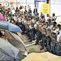 示威者撐起雨傘與數十名防暴警察在隧道中對峙。