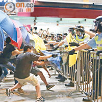 旺角<br>示威者撐起雨傘與持警棍的警員對峙。