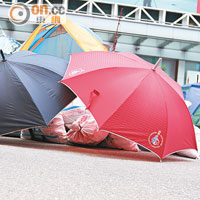 帳篷旁多袋碎石有雨傘遮掩。
