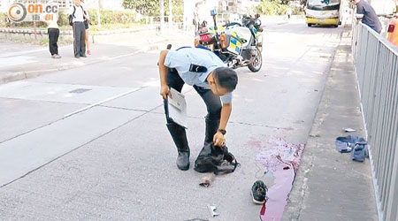 警員檢視死者遺留路中的物件。（李子強攝）