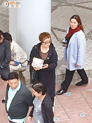 陳姓女子被拍攝到手捧兩大疊鈔票呆站路旁。（讀者提供）
