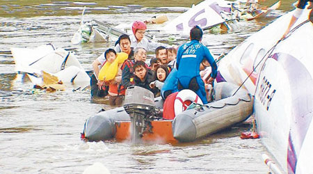 林明威（抱男童者）與黃金順等多名生還者在飛機殘骸上等待救援。（互聯網圖片）